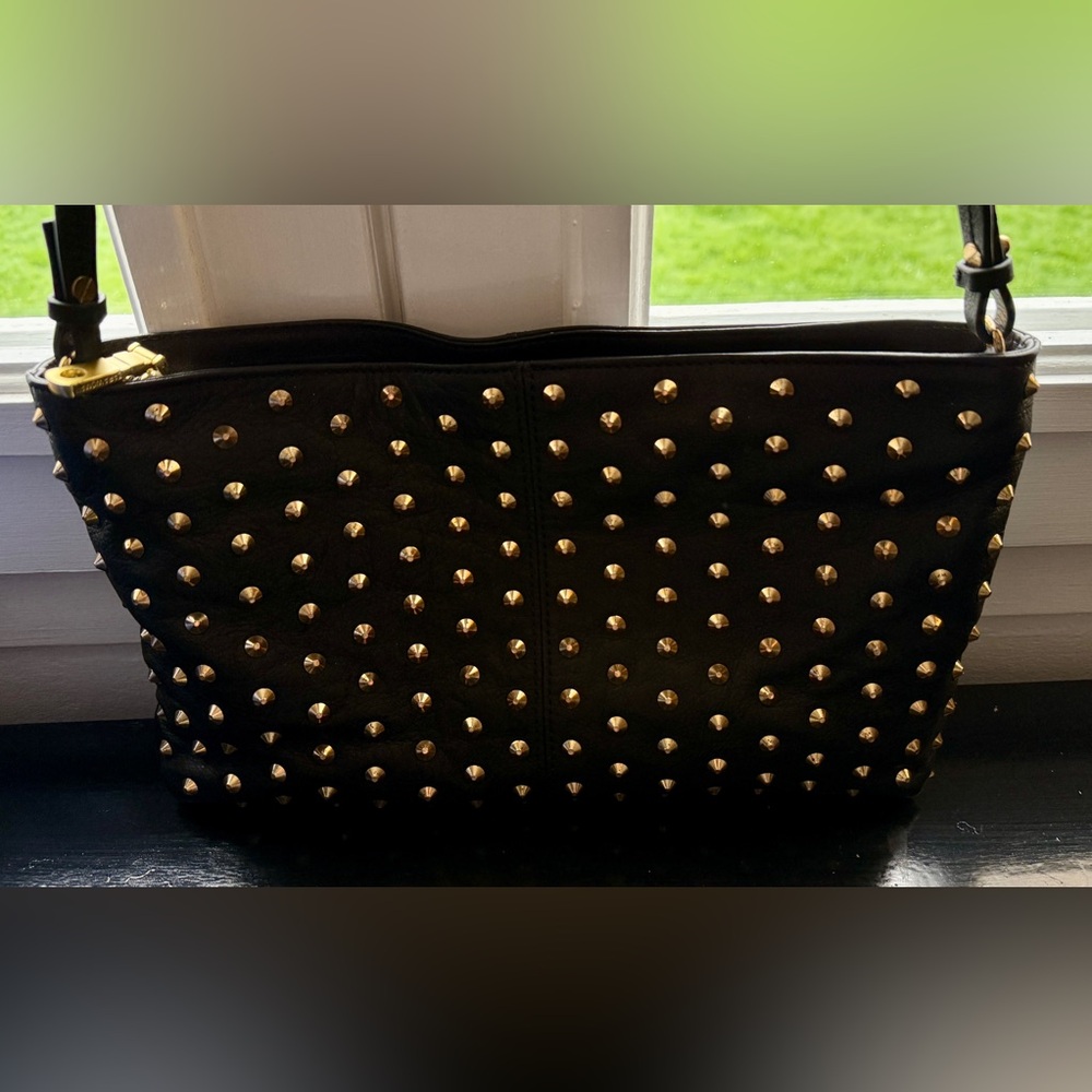 Crossbody or shoulder bag in black leather with gold studs.